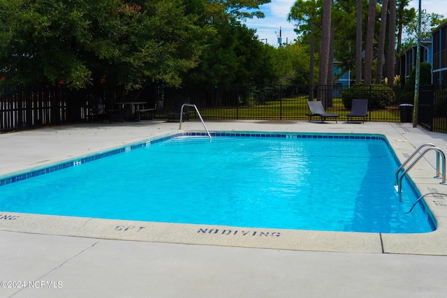 community pool with a patio area and fence