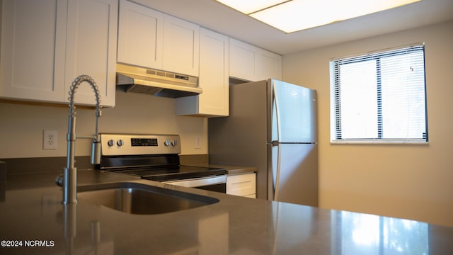 kitchen featuring dark countertops, under cabinet range hood, white cabinetry, and stainless steel appliances