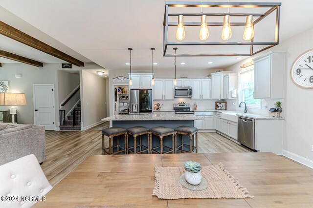 kitchen featuring stainless steel appliances, a kitchen island, decorative light fixtures, a breakfast bar area, and light hardwood / wood-style flooring