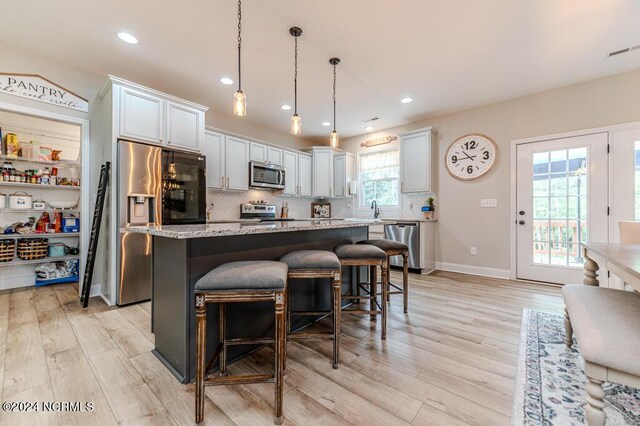 kitchen with pendant lighting, white cabinetry, a kitchen island, and appliances with stainless steel finishes