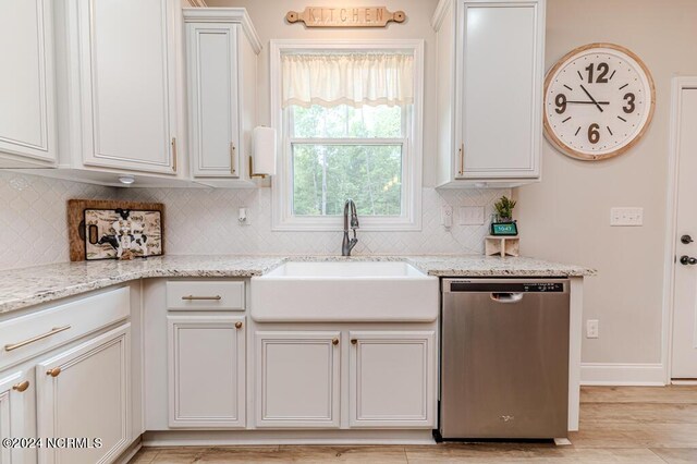 kitchen with stainless steel dishwasher, light stone countertops, white cabinets, and sink