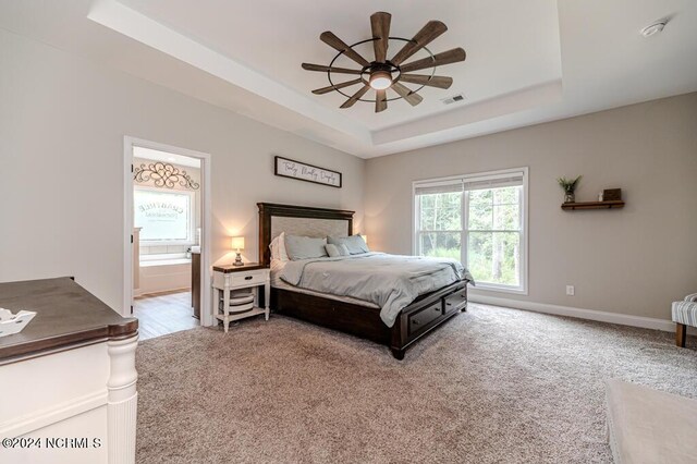 bedroom featuring ensuite bathroom, carpet floors, ceiling fan, and a tray ceiling