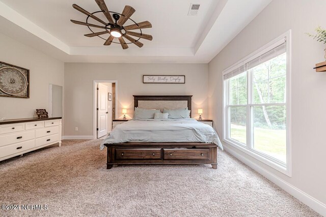 bedroom featuring ceiling fan, multiple windows, and light colored carpet