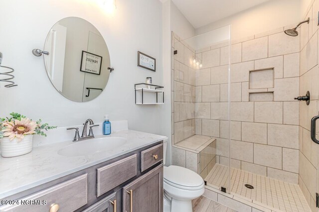 bathroom featuring toilet, vanity, and a shower with door