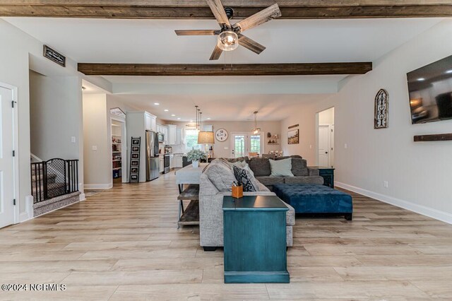 living room featuring light hardwood / wood-style floors, beamed ceiling, and ceiling fan