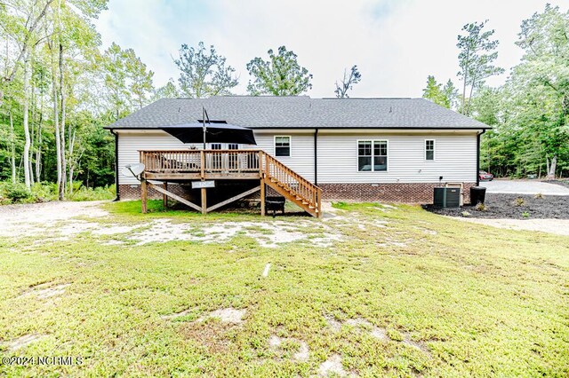 rear view of property with central AC unit, a wooden deck, and a yard