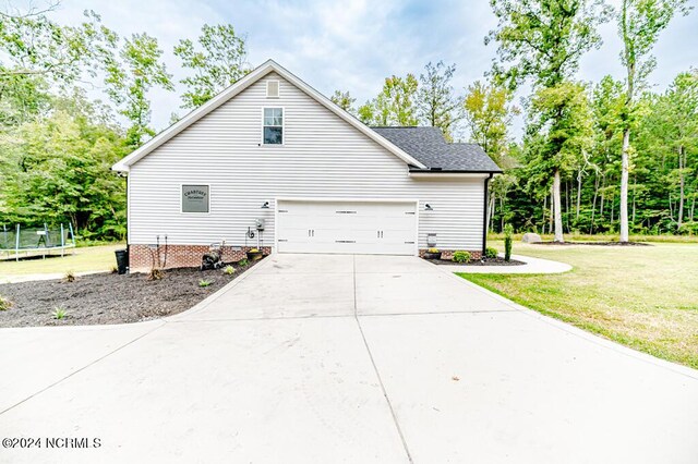 view of side of property with a garage, a yard, and a trampoline