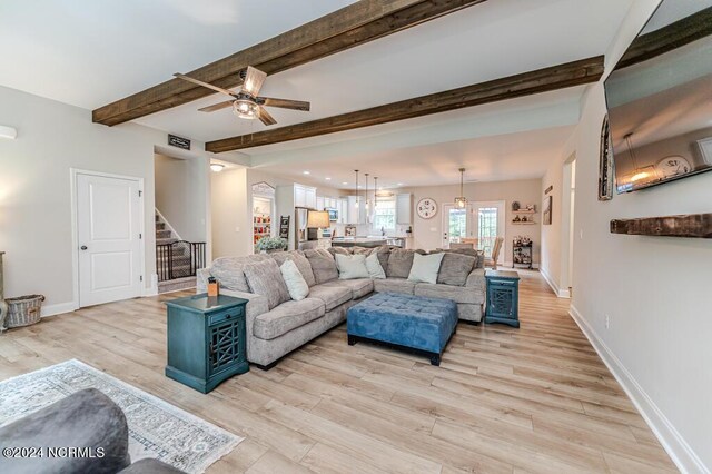 living room with ceiling fan, light hardwood / wood-style floors, and beam ceiling