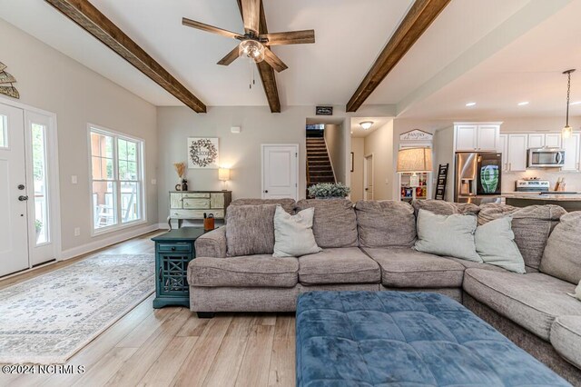 living room with ceiling fan, beam ceiling, and light wood-type flooring