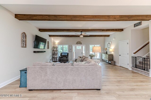 living room with ceiling fan, beam ceiling, and light wood-type flooring