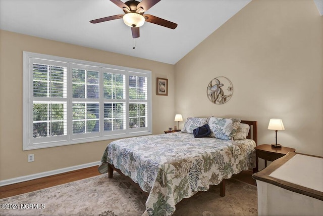 bedroom with multiple windows, vaulted ceiling, baseboards, and wood finished floors