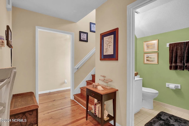 bathroom featuring toilet, wood-type flooring, and a textured ceiling