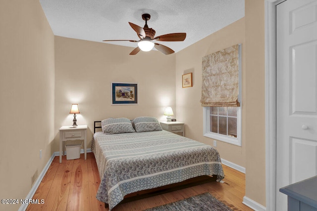 bedroom featuring ceiling fan, light hardwood / wood-style floors, and a textured ceiling