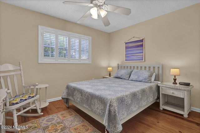 bedroom with ceiling fan, a textured ceiling, wood finished floors, and baseboards