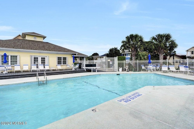 community pool with a patio area and fence