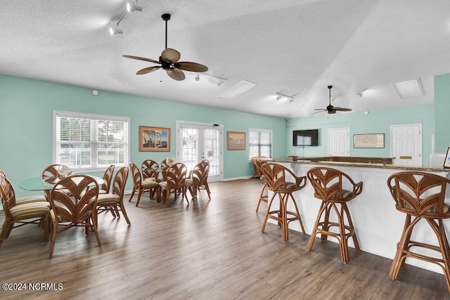 dining room featuring bar area, ceiling fan, dark hardwood / wood-style floors, and a textured ceiling