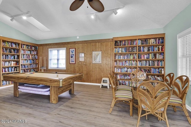 game room with a textured ceiling, wooden walls, wood finished floors, a ceiling fan, and vaulted ceiling