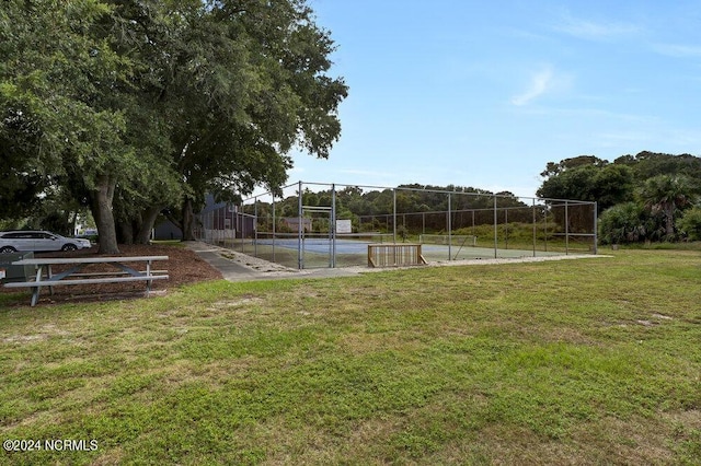 view of home's community featuring a tennis court, a lawn, and fence