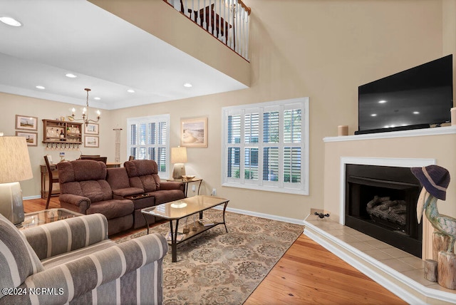 living room featuring a tiled fireplace, a chandelier, and light hardwood / wood-style floors