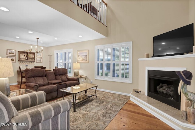 living area featuring a chandelier, a tile fireplace, wood finished floors, and baseboards