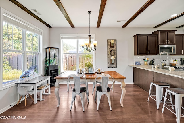 dining room with dark hardwood / wood-style floors, an inviting chandelier, and beamed ceiling