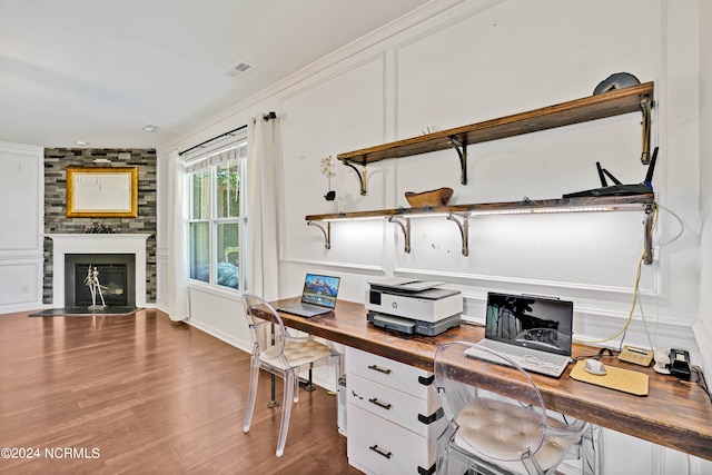 office with a large fireplace, wood-type flooring, and ornamental molding