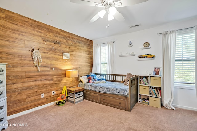 bedroom with wood walls, ceiling fan, and carpet