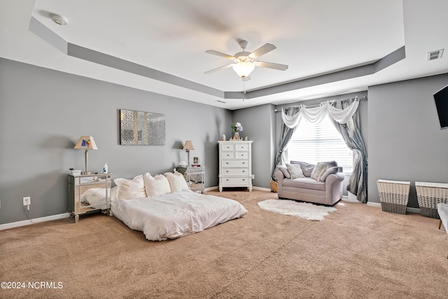 carpeted bedroom featuring a raised ceiling and ceiling fan