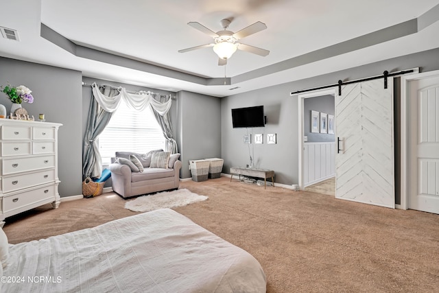 carpeted bedroom featuring a barn door, ceiling fan, and a raised ceiling