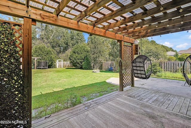 wooden terrace with a pergola, a yard, and a trampoline