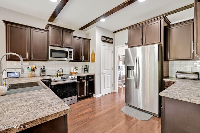 kitchen featuring beam ceiling, stainless steel appliances, sink, hardwood / wood-style flooring, and dark brown cabinetry