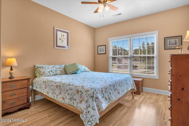 bedroom featuring a ceiling fan, light wood-style flooring, baseboards, and visible vents