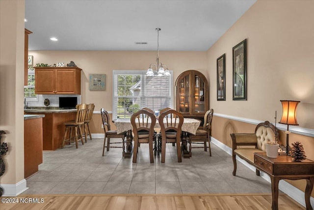 dining area with light tile patterned floors, a notable chandelier, visible vents, and baseboards