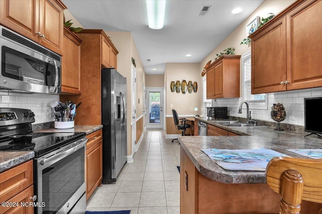 kitchen featuring dark countertops, brown cabinets, stainless steel appliances, and a sink