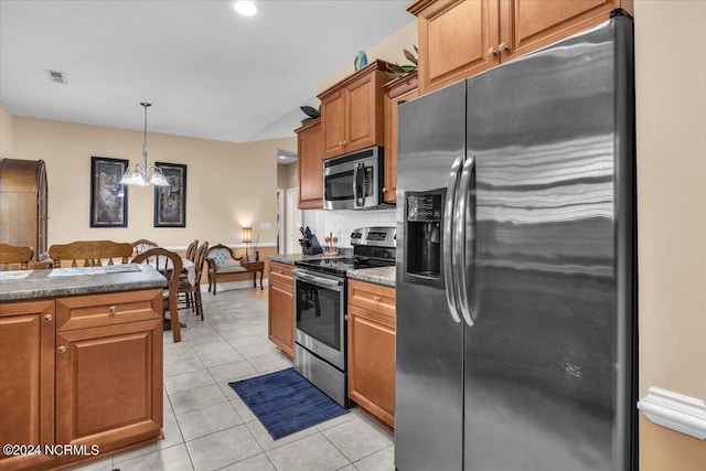 kitchen featuring brown cabinets, decorative light fixtures, backsplash, stainless steel appliances, and light tile patterned flooring