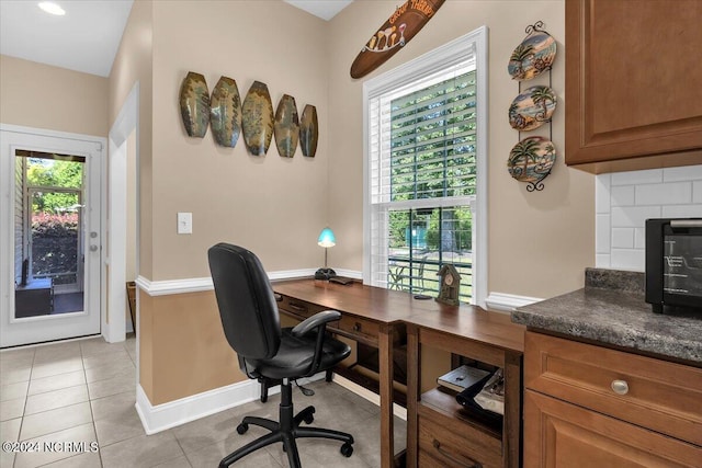 home office with light tile patterned floors, baseboards, and a healthy amount of sunlight