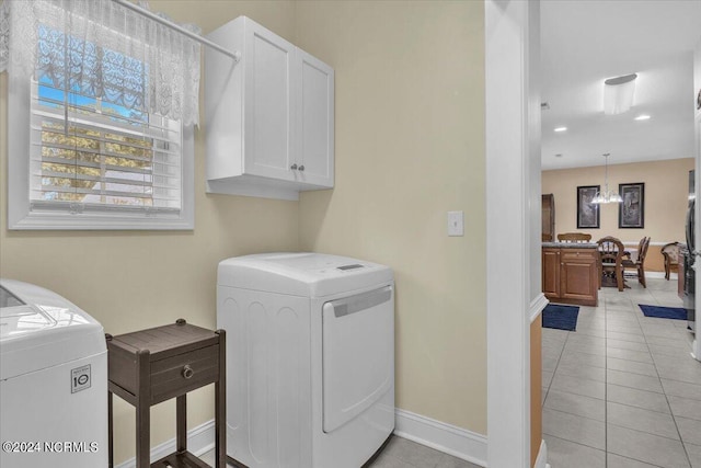 washroom featuring washer and clothes dryer, cabinet space, light tile patterned flooring, baseboards, and a chandelier