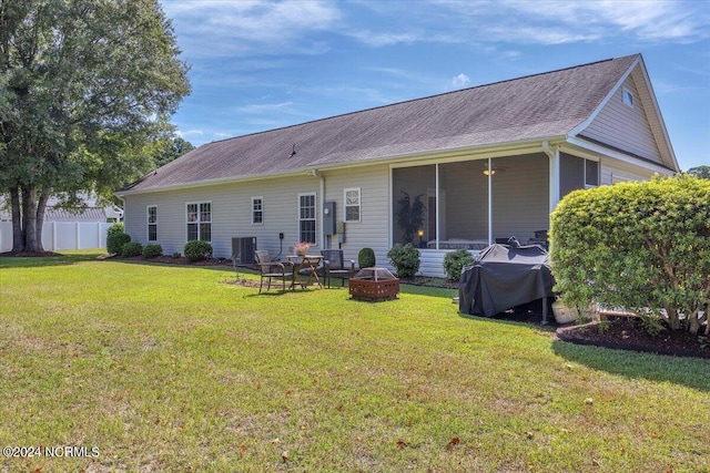 back of house featuring a fire pit, fence, central AC unit, a lawn, and a sunroom