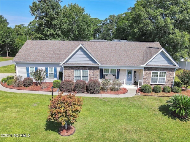 single story home with stone siding, roof with shingles, a porch, and a front lawn