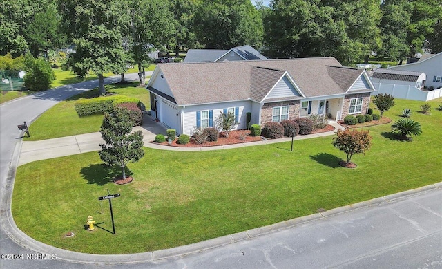 view of front facade with fence, concrete driveway, a front yard, stone siding, and an attached garage