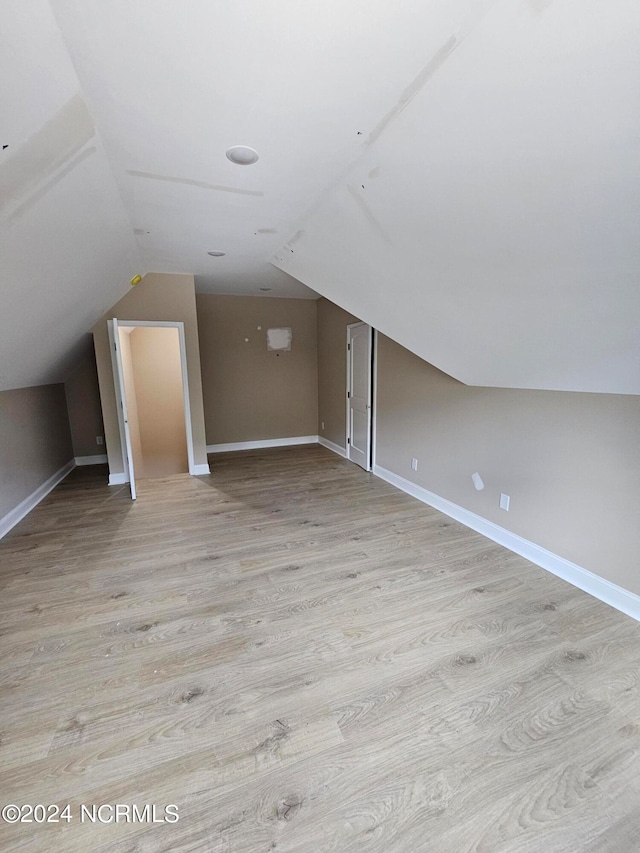 bonus room with vaulted ceiling and light wood-type flooring