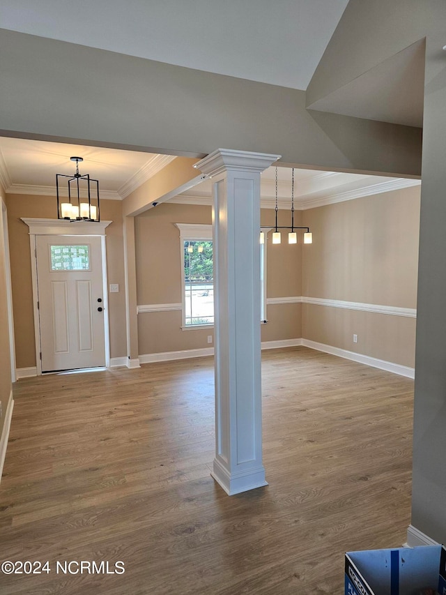 foyer with an inviting chandelier, ornamental molding, hardwood / wood-style floors, and decorative columns