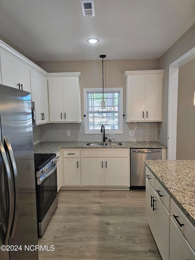 kitchen with sink, stainless steel appliances, light stone countertops, light hardwood / wood-style floors, and white cabinets