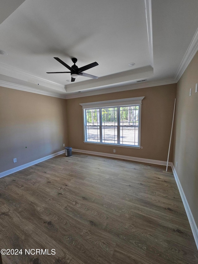 spare room with crown molding, a tray ceiling, dark wood-type flooring, and ceiling fan