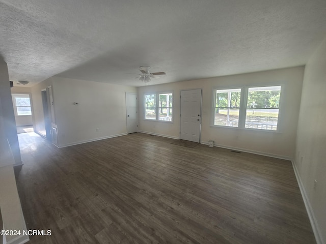 unfurnished living room featuring a textured ceiling, a ceiling fan, baseboards, and dark wood-style flooring