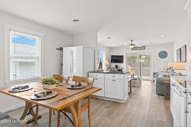 kitchen featuring white cabinetry, plenty of natural light, light hardwood / wood-style floors, and white fridge