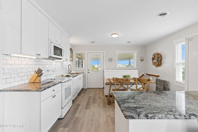 kitchen with light hardwood / wood-style flooring, white appliances, dark stone counters, decorative backsplash, and white cabinets