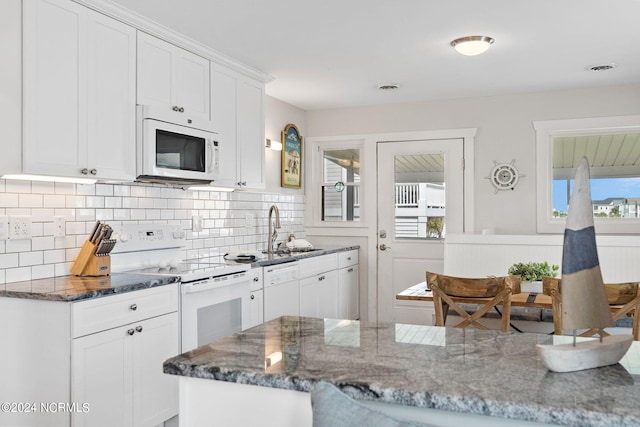 kitchen with white appliances, dark stone counters, sink, and white cabinets