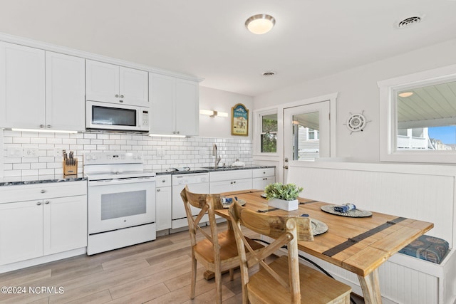 kitchen featuring a healthy amount of sunlight, sink, white cabinets, and white appliances