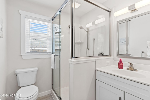 bathroom featuring vanity, toilet, and a shower with door